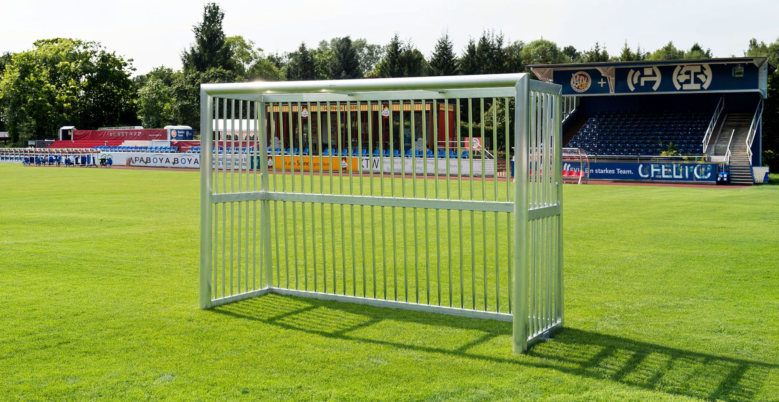 Aluminium Bolzplatztor auf Naturrasen vor Vereinstribüne, Gitterrückwand, freistehend, Frontansicht