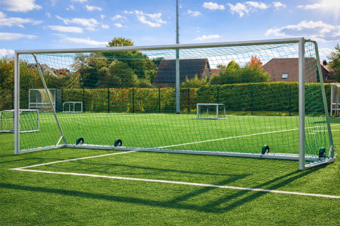 Großfeld-Fußballtor Safety mit Kippschutz aus Aluminium auf einem Kunstrasenplatz, Rückansicht mit Tornetz und Transportrollen