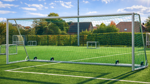 Großfeld-Fußballtor Safety mit Kippschutz aus Aluminium auf einem Kunstrasenplatz, Rückansicht mit Tornetz und Transportrollen