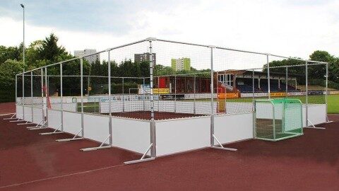 Mobile Soccer Courts Arena Mobil kaufen, Stecksystem, TÜV-geprüft, Soccer Eventsport Mobiler Soccer Court Arena Mobil auf Tartanplatz vor Stadiontribüne, weißes Aluminium-Bandensystem, umlaufendes Netz, urbane Umgebung