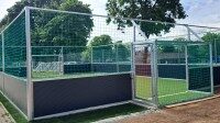 Soccer Court stationär kaufen, überdacht mit Kunstrasen, Soccer Eventsport Stationärer Soccer Court mit weißen Banden, umlaufendem Netz und Überdachung, grüner Kunstrasen, Fußballtor mit Vereinsbranding in der Mitte, Innenansicht von der Längsseite