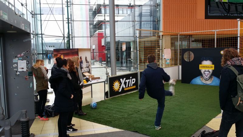 Mitarbeiter beim Torwandschießen in einer Halle während eines Betriebsfeste