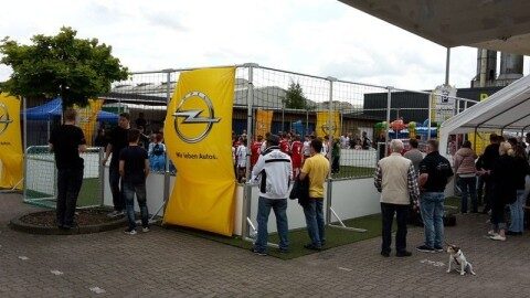 Besucher eines Firmenevents vor einem Soccer Court mit Opel-Branding im Außenbereich