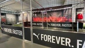 Innenansicht eines Soccer Courts mit vollflächigem Puma-Branding auf den Banden, Netz und Schaufenster im Hintergrund
